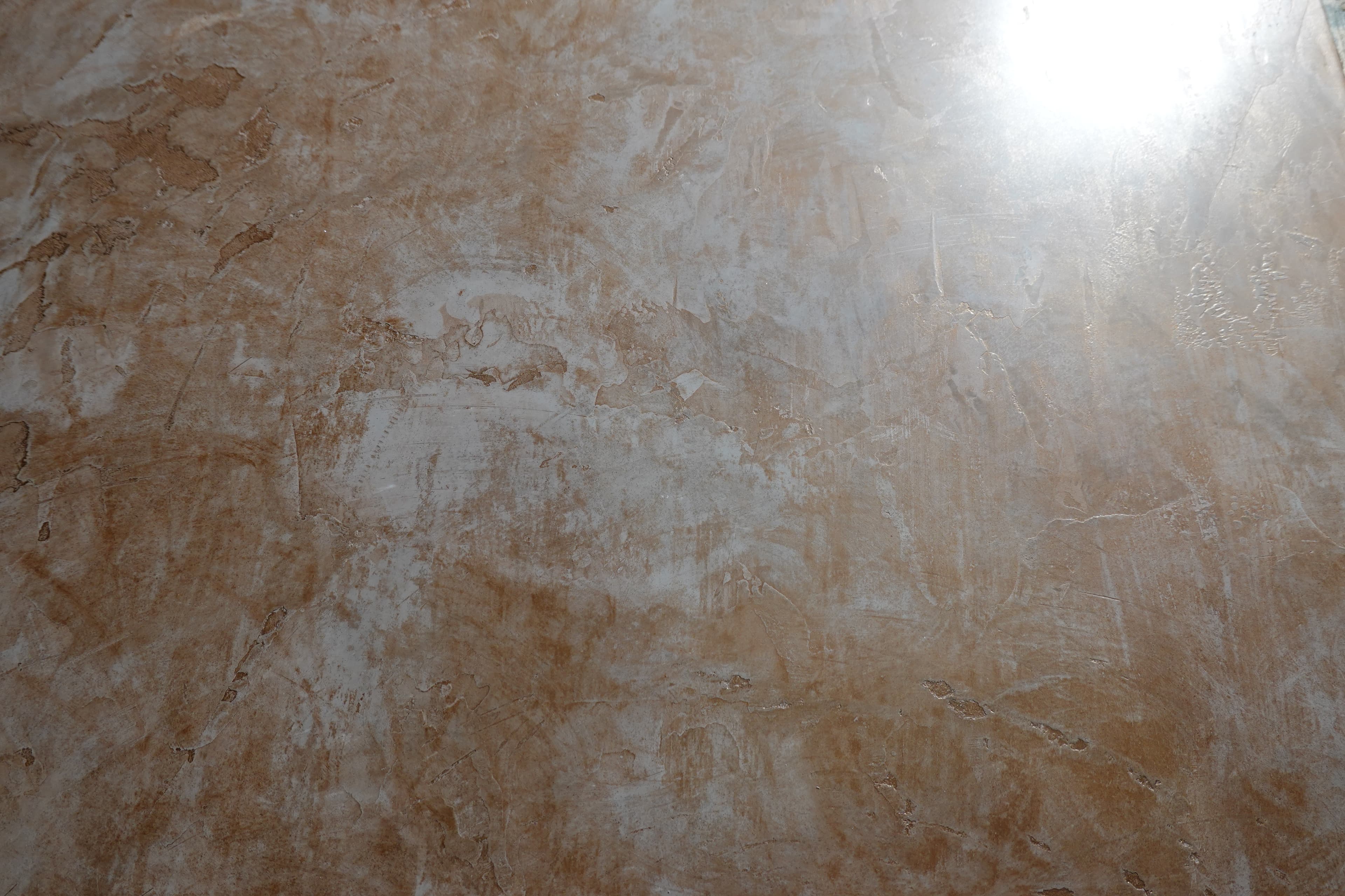 A Marmorino Fine lime-plaster surface in warm terracotta, polished to a sheen with pale mineral clouding through it.